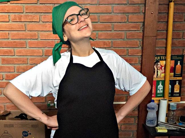 Marina Monaco mulher com mãos na cintura sorrindo vestida com avental de cozinheiro