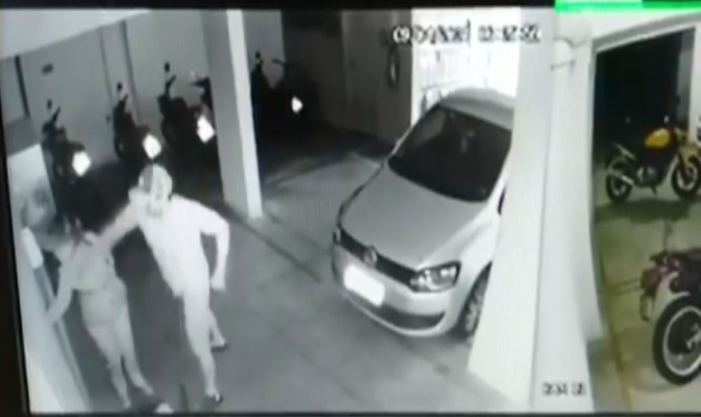 Print em preto e branco da câmera se de segurança do prédio. Na imagem, o homem dá um soco no rosto da mulher