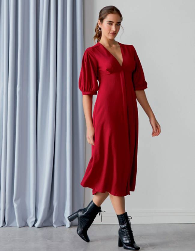 vestido.png Mulher caminha com vestido vermelho olhando para câmera