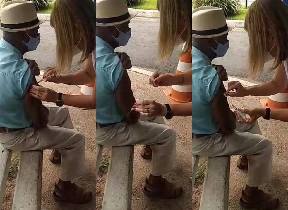 Enfermeira aplica agulha no braço de idoso, mas não aperta o pistão da seringa