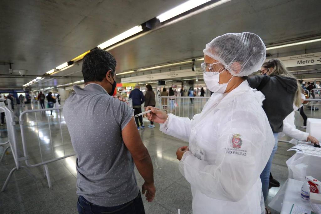 Imagem mostra enfermeira aplicando dose de vacina contra a Covid-19 em estação do Metrô