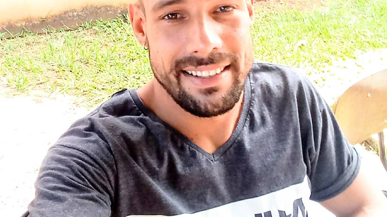 Imagem apresenta Paulo tirando uma selfie, em que aparece metade superior do seu corpo. Ele está sorrindo para a câmera.