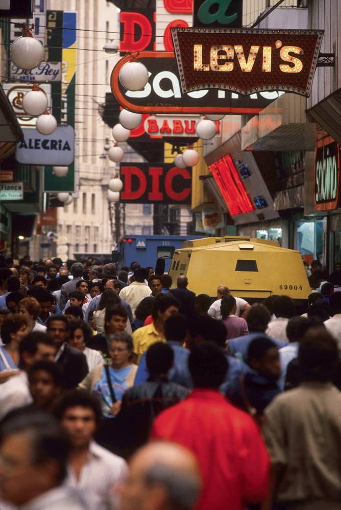 manual-do-centro-rua-direita-lei-cidade-limpa foto da rua direita, lotada de pessoas, com diversas placas de anúncio de marcas sobre suas cabeças