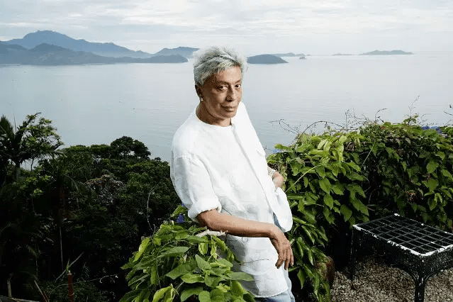 clodovil1 Homem posa de branco em cima de uma casa que tem vista para o oceano