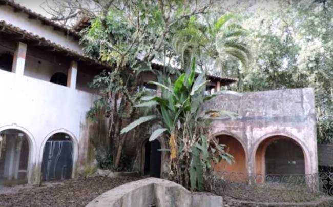 Casa abandonada em meio a árvores e plantas sem cuidados