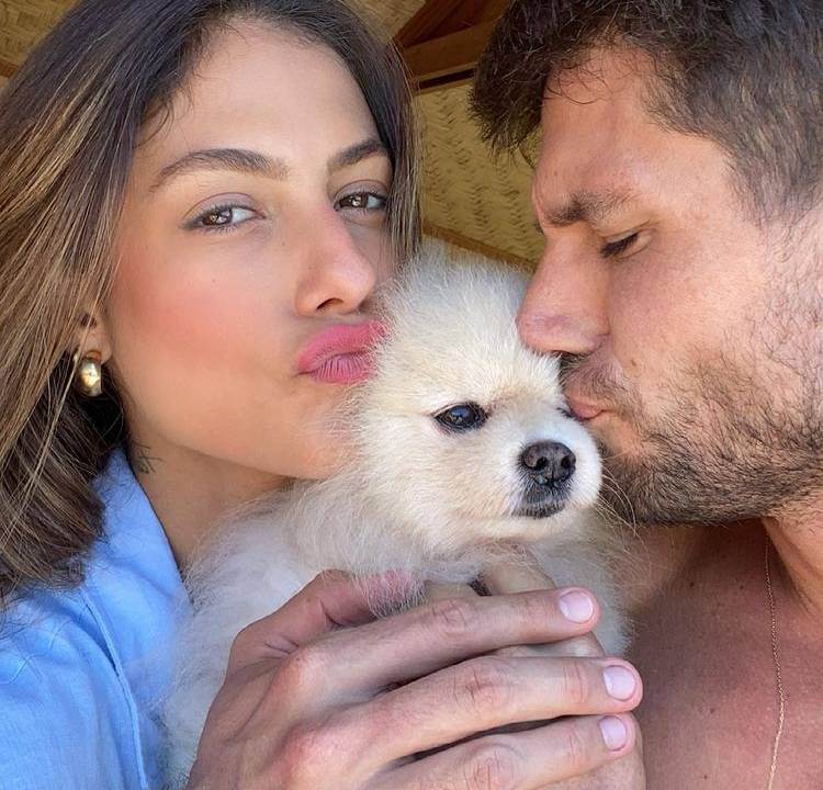 mari gonzalez e seu marido, Jonas, posando para a foto enquanto beijam o cachorro Marsh