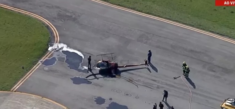 Imagem aérea do Campo de Marte. É possível ver o helicóptero tombado, ainda que inteiro, e pessoas em volta do veículo.