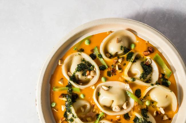 Foto tirada de cima de cumbuca com tortelloni ao creme de abóbora com pesto e sementes por cima, da Green Kitchen.