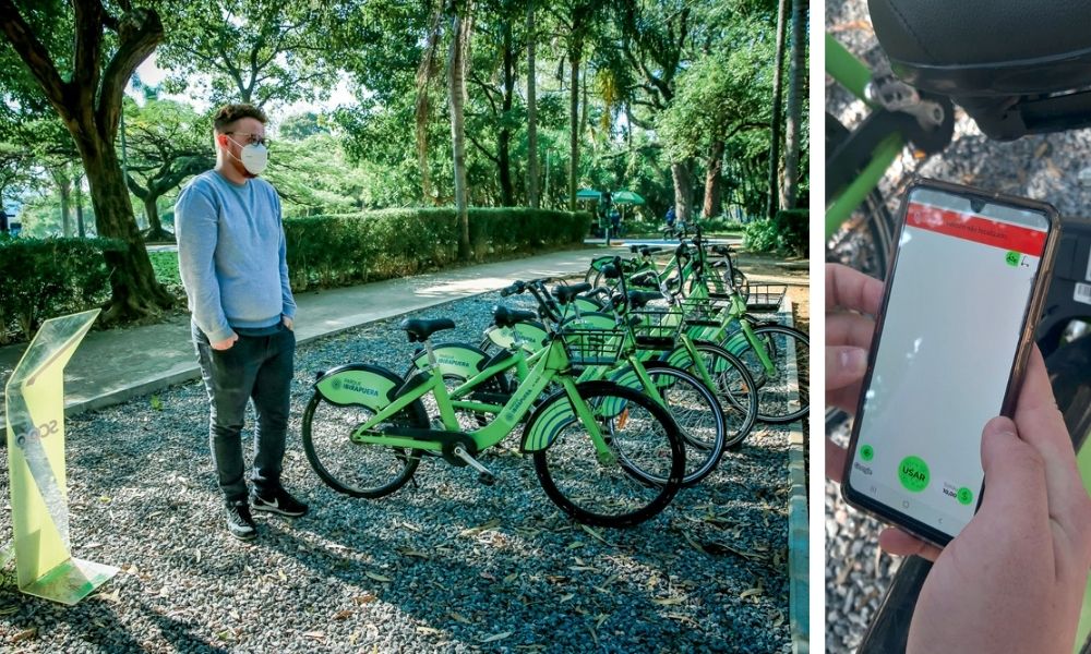 IBIRAPUERA lucas aluguel bike app A imagem mostra Lucas em frente as bikes que podem ser alugadas e, à direita, há uma foto de seu celular aberto no aplicativo, com tela predominantemente branca.