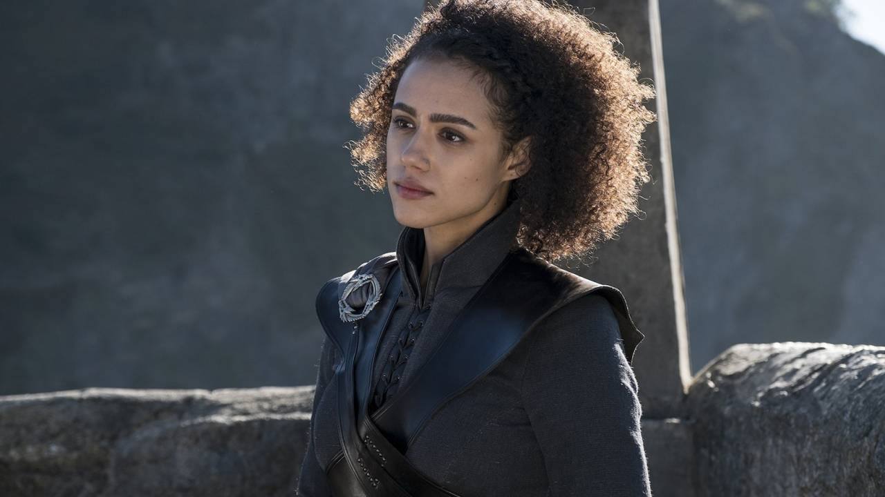 Atriz Nathalie Emmanuel em cena de filme, veste roupas pretas e penteado black power.