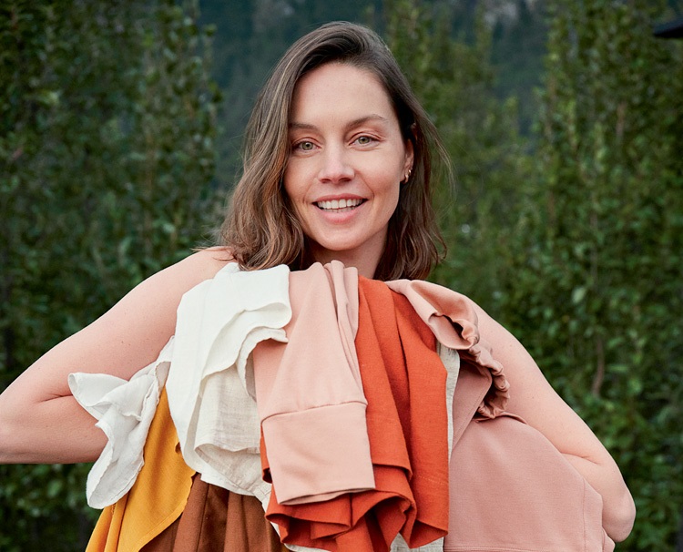 patrícia beck posando para foto sorrindo e segurando diversas roupas