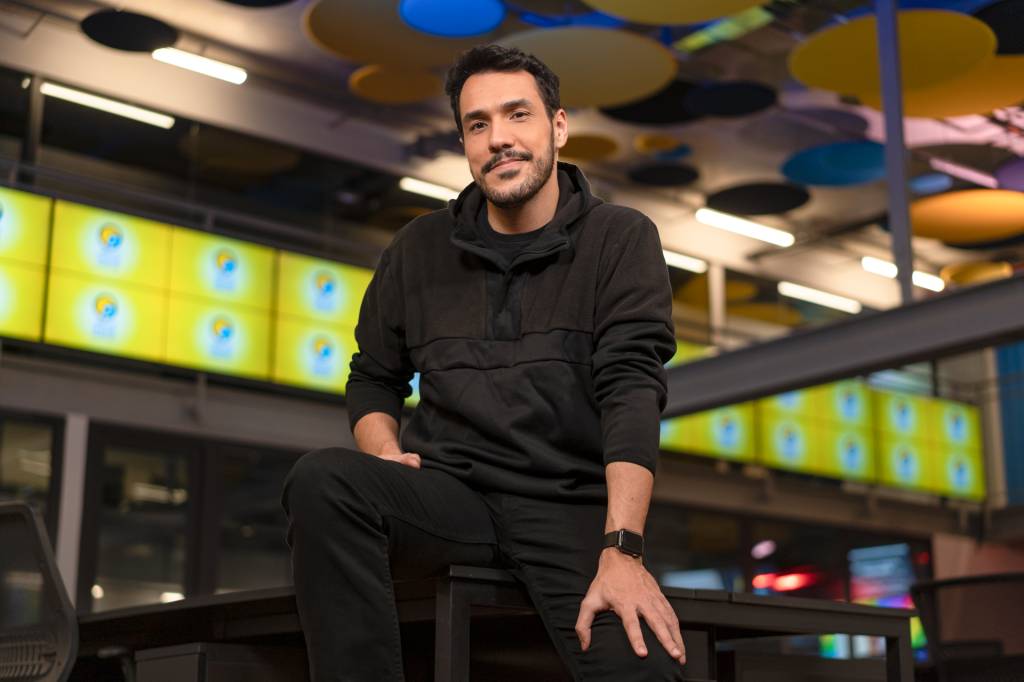 Rafa Dias (DIVULGAÇÃO) Empresário Rafa Dias posa em um escritório com telas ao fundo. Veste roupas pretas, relógio e sorri para a câmera.