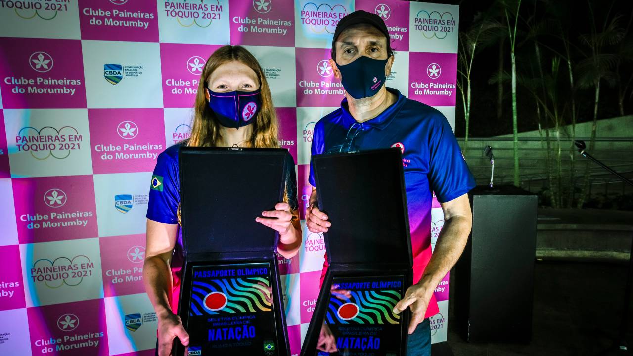 A imagem mostra Stephanie e Wlad, ambos segurando placas olímpicas e mostrando elas para a câmera