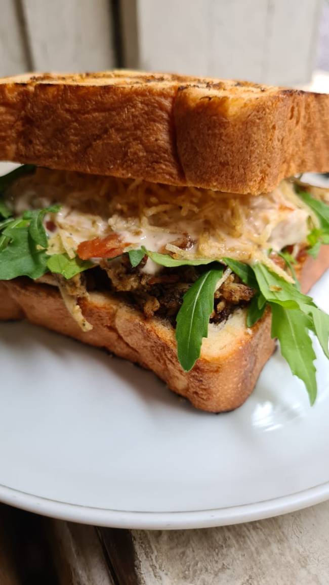 Holy Burger Sanduíche feito no pão de forma de brioche sobre prato de louça branca.