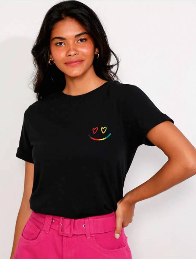 Menina veste camiseta preta com um emoji de sorriso nas cores da bandeira LGBT