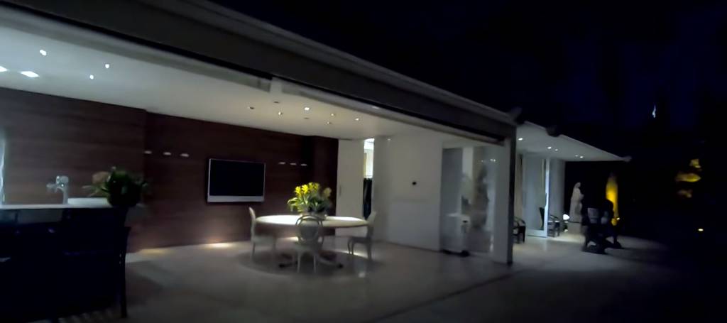 casa-hebe-camargo-parte-externa área externa da casa, com abertura entre os ambientes interno e externo e uma televisão e mesa redonda na parte coberta
