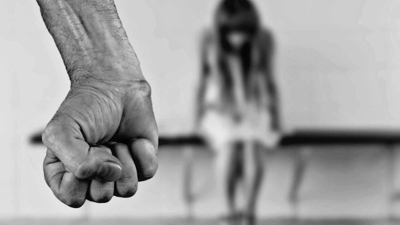 Imagem mostra homem de punho cerrado e, ao fundo, menina sentada em banco