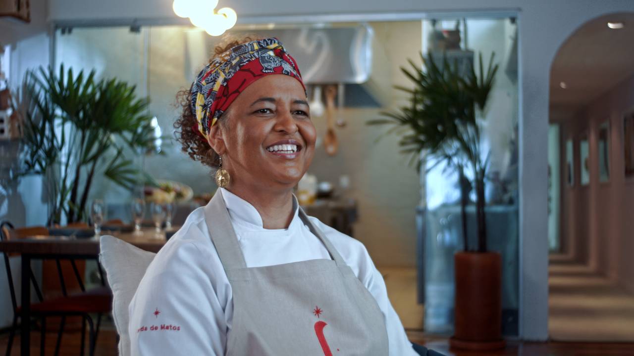 A chef Ieda de Matos sentada sorrindo.