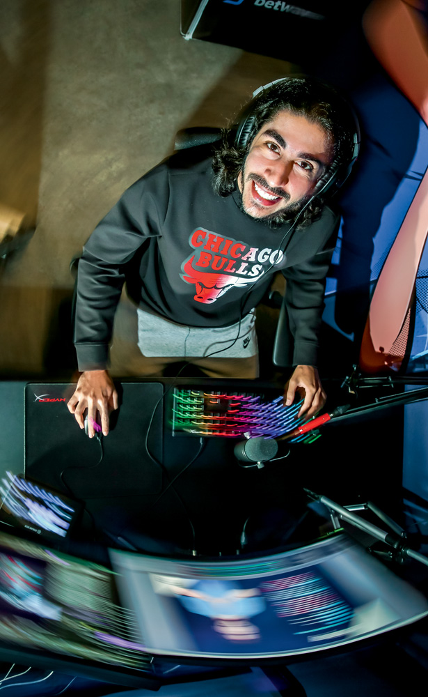 Gabriel Gomes, o Baiano: aposentadoria do profissional após problema de saúde A imagem é uma foto tirada de cima de Baiano. Ele está olhando para cima, sentado em frente ao seu monitor, com um teclado colorido e sorrindo.