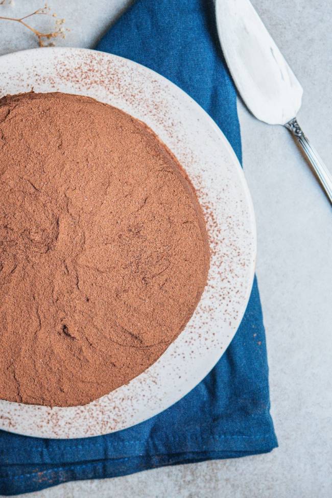 Helô Bacellar – devil’s cake Foto aérea de bolo de chocolate em prata de louça branca sobre toalha azul.