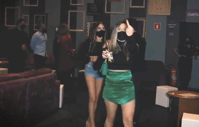 Mulher mostra o dedo do meio durante blitz da força-tarefa. Ela, que segurava uma garrafa de cerveja, vestia saia verde e blusa preta.