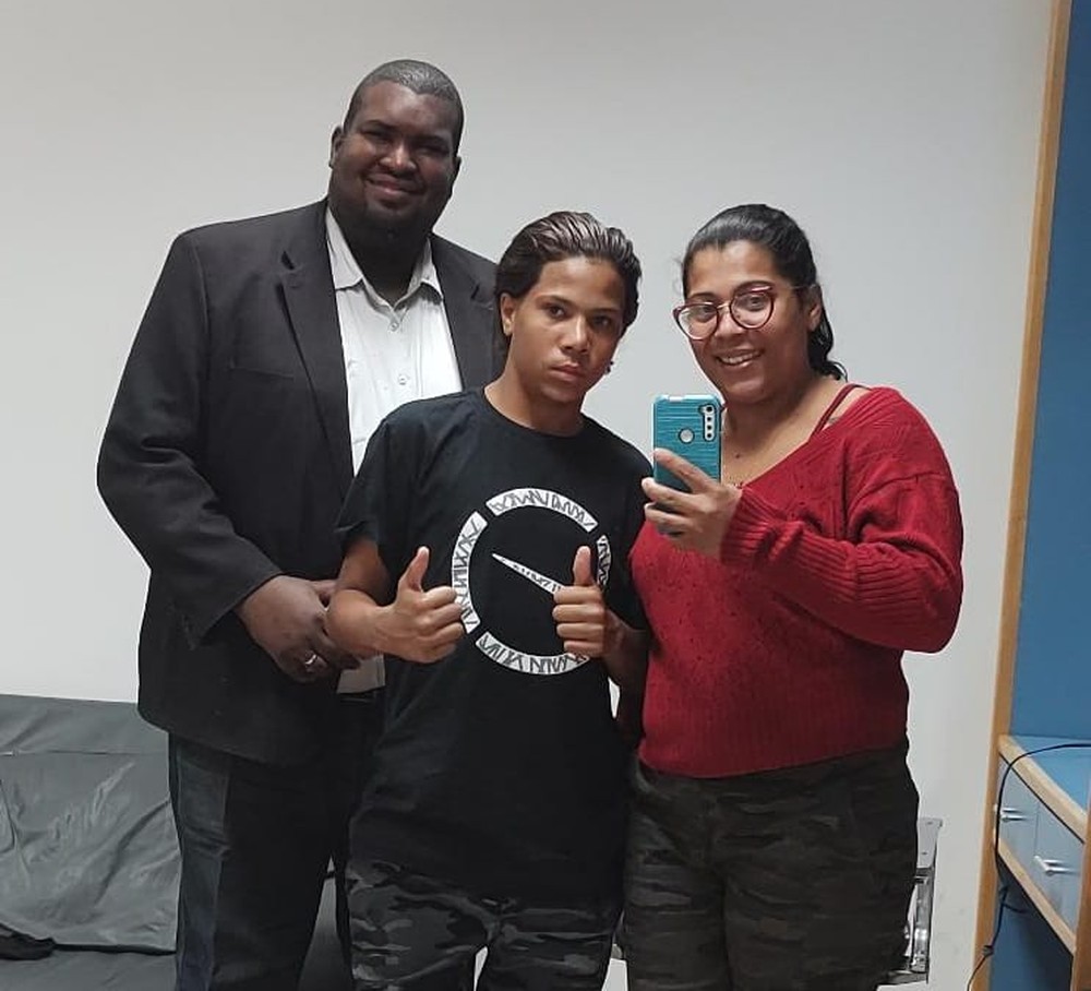 sandro-moraes-joão-victor-mãe-nota-falsa-100-reais sandro moraes posando com joão victor e sua mãe, priscila. joão está entre os dois e estão todos juntos posando para a foto