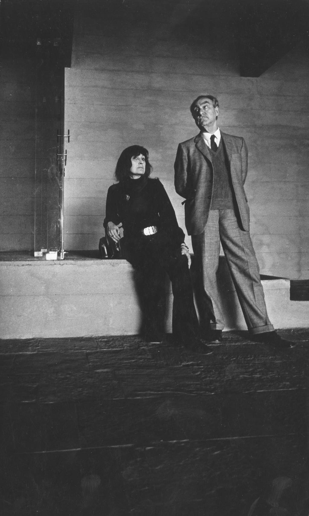 Pietro Maria Bardi, diretor do Masp, com a esposa Lina Bo Bardi, arquiteta. A imagem mostra Lina e Pietro, com posturas desleixadas, dentro do Masp, com o olhar perdido em direções diferentes.