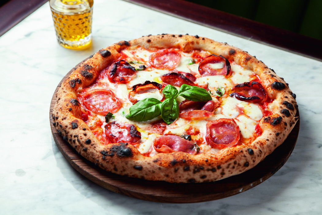 Pizza individual com queijo, salame, molho de tomate e manjericão.