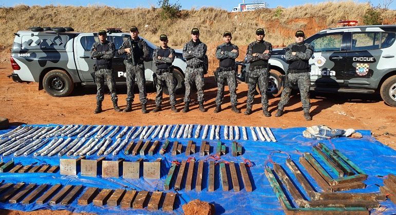 policiais do gate posando para a foto com explosivos apreendidos sobre uma lona azul no chão, em aterro sanitário em Araçatuba