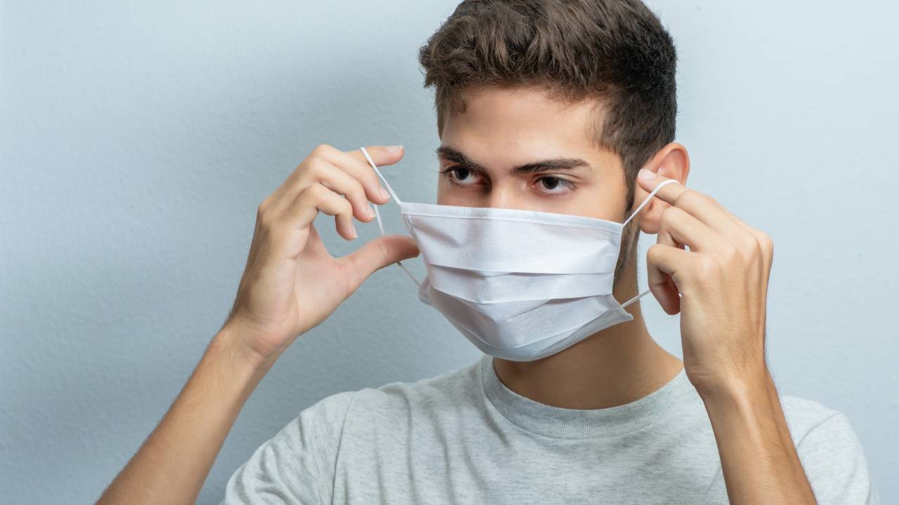 Imagem mostra garoto colocando a máscara facial de proteção