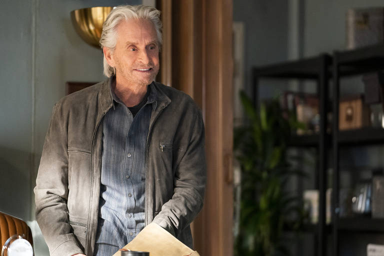 Imagem mostra Michael Douglas usando camisa e blusa aberta, em quarto, durante gravações de O Método Kominsky