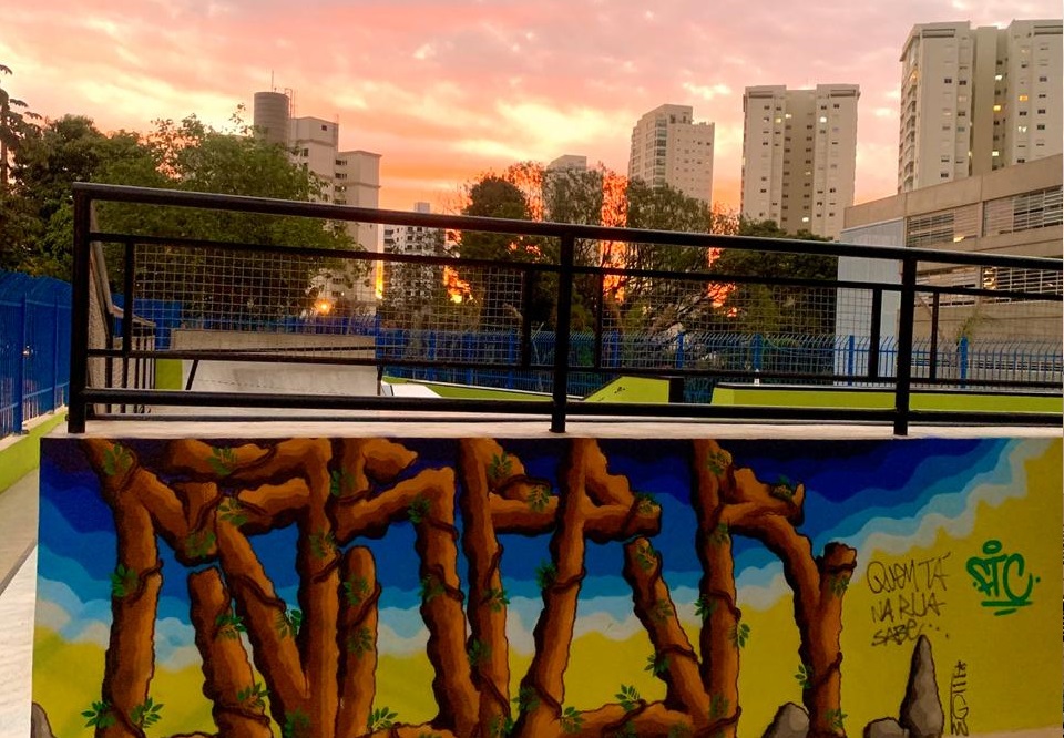 pista de skate ZL Foto mostra pedaço de uma pista de skate. Em uma parede, há grafite e o céu tem um por do sol alaranjado