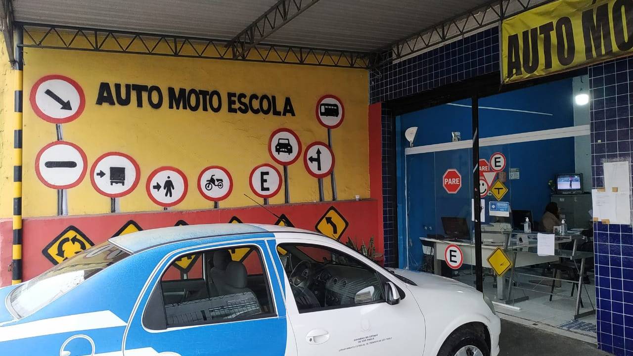 imagem de entrada de automotoescola, com pintura na parede indicando e carro estampado com marca do detran.sp parado na frente