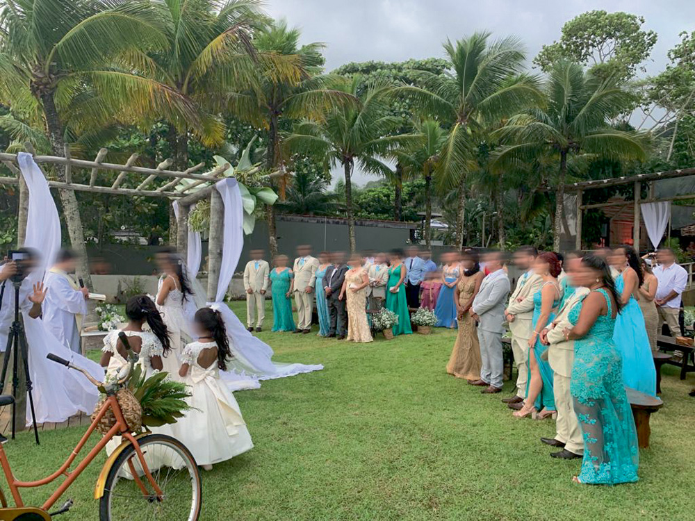 Sunset Bistrô Foto mostra uma cerimônia de casamento em um gramado na praia. Convidados observam o altar