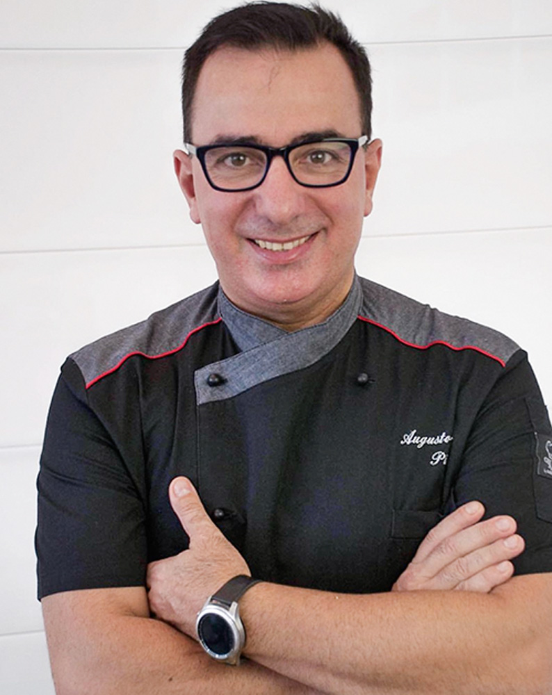 Augusto Piras O chef Augusto Piras de dólmã preto e braços cruzados.