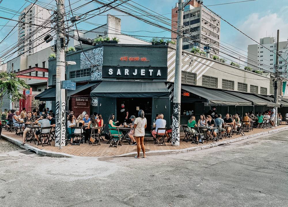 Fachada do bar com mesas espalhadas ao longo da calçada do imóvel de esquina