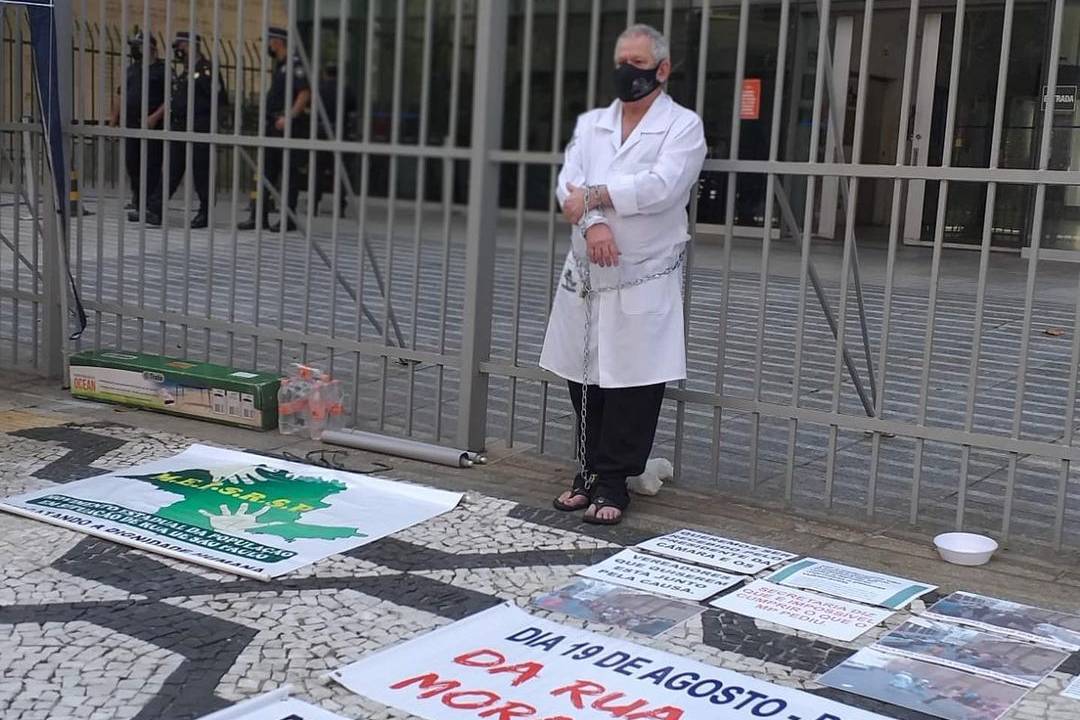 A imagem mostra Robson acorrentado em frete à câmera municipal de São Paulo