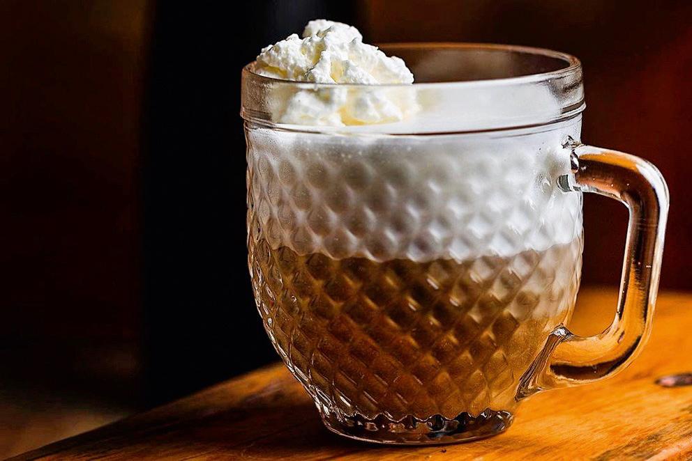 Em uma caneca de vidro, o mocha é servido com uma camada de creme e chantilli no topo