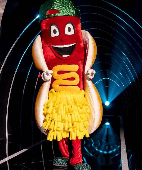 Imagem mostra homem fantasiado de cachorro-quente que usa boné