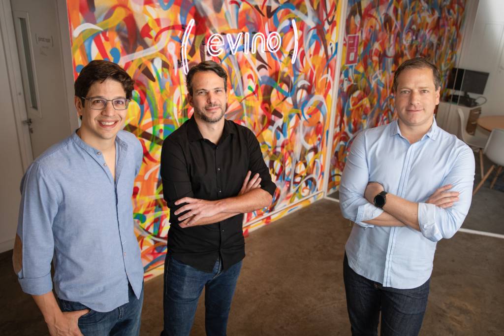 Marcos Leal (óculos), Ari Gorenstein (camisa preta) e Alexandre Bratt, posam no escritório da Evino, em São Paulo, Brasil.