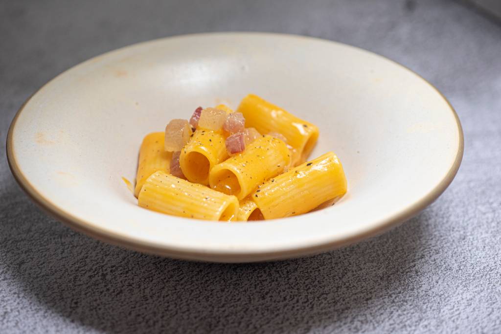 Prato fundo de cerâmica com rigatoni carbonara.