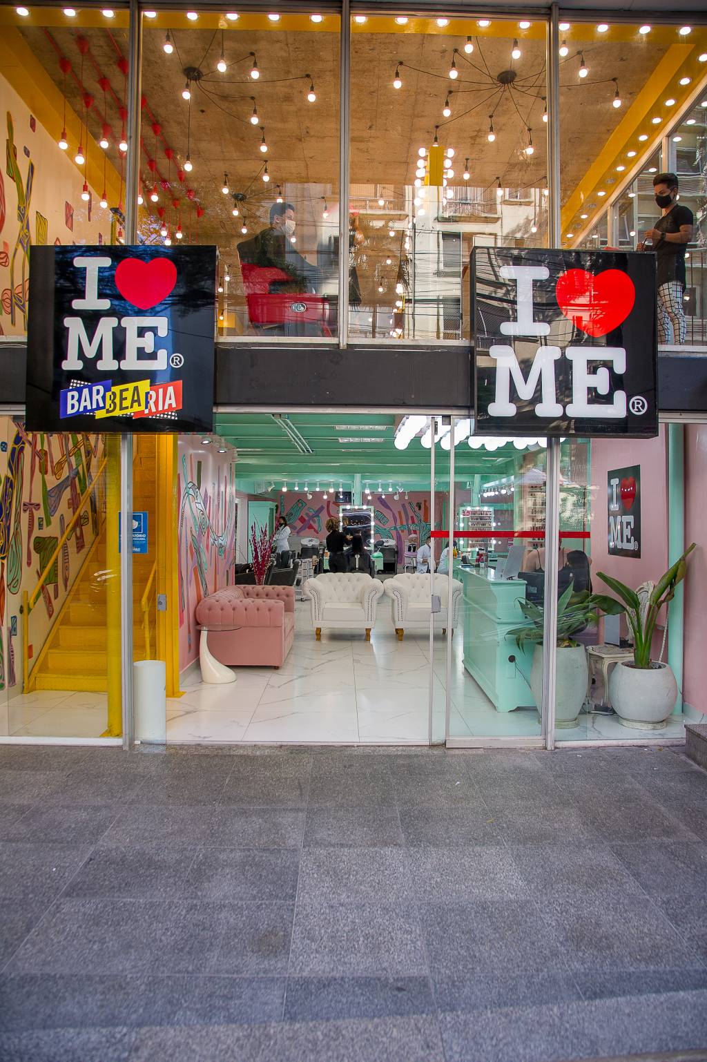 Fachada da barbearia I love Me: envidraçada, com dois logotipos I coração Me.