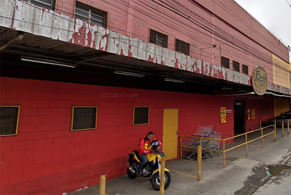 Imagem mostra fachada de supermercado, com motociclista parado