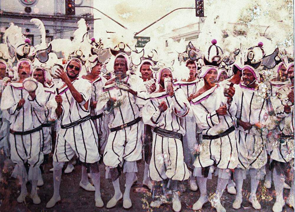 foto antiga de homens com fantasia branca tocando instrumentos conjuntamente