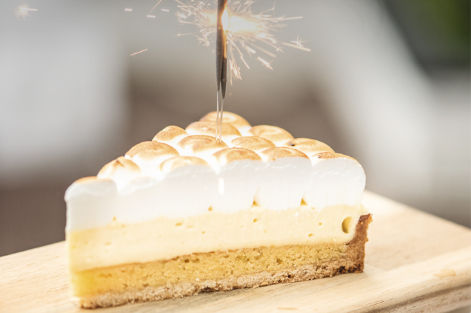 Fatia de torta de limão com vela de estrela acesa em cima.