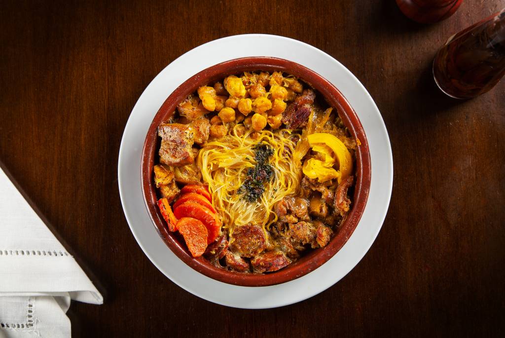 Achados ELO – Carmen La Loca Foto aérea de cocido madrileno com carnes, cenoura, repolho, grão-de-bico e macarrão.