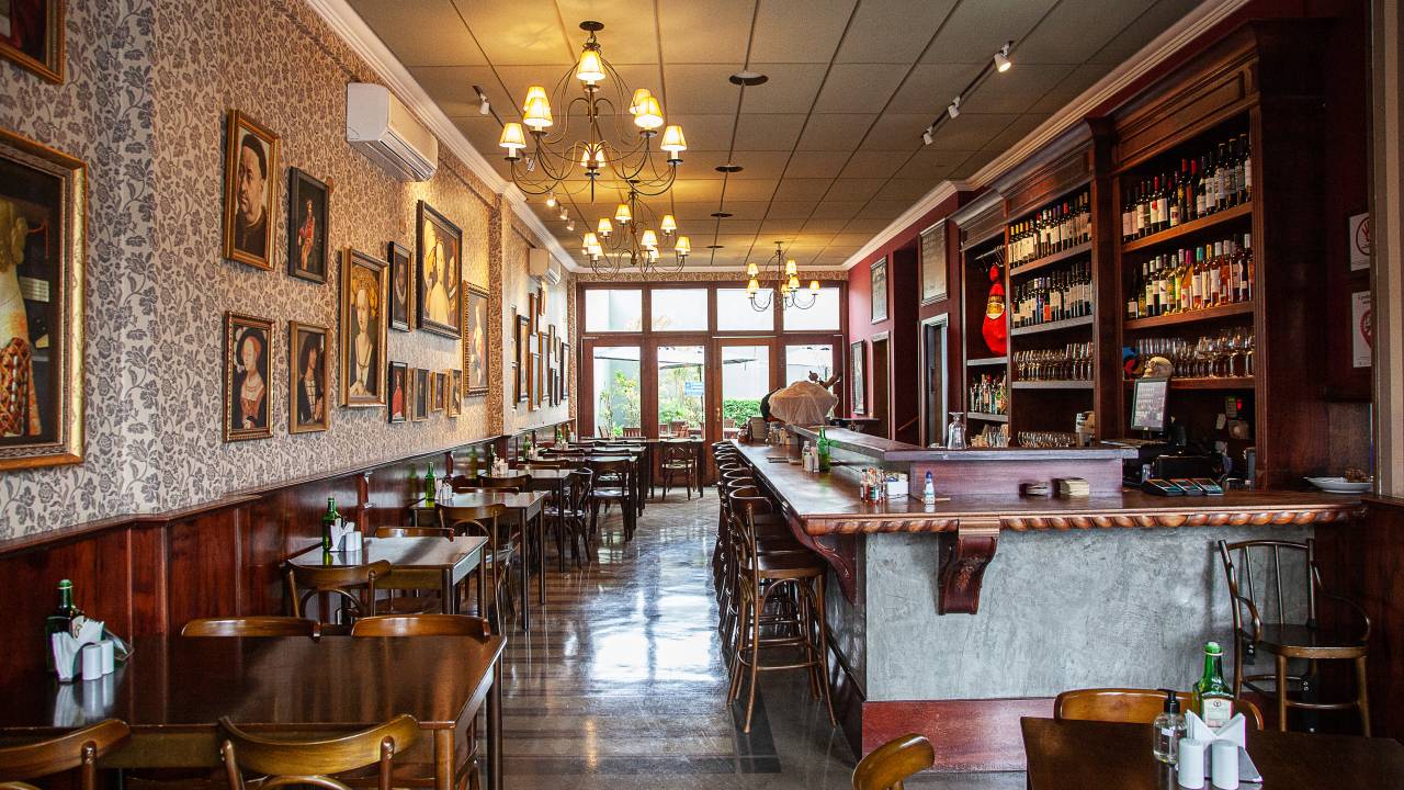 Salão do restaurante Carmen La Loca, com bancada à direita e mesas de madeira à esquerda.