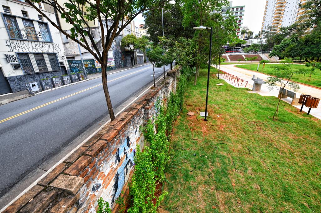 Muro do parque divide gramado e rua.