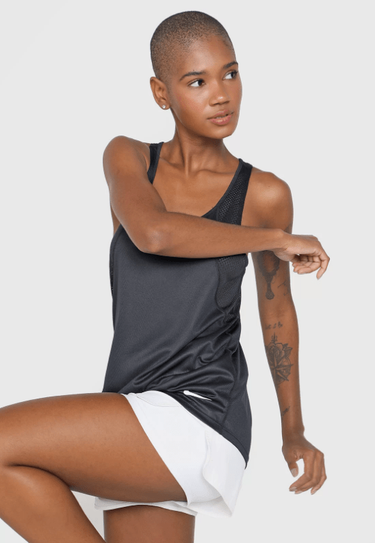 REGATA feminina Uma mulher negra se alonga utilizando uma regata cinza e shorts branco