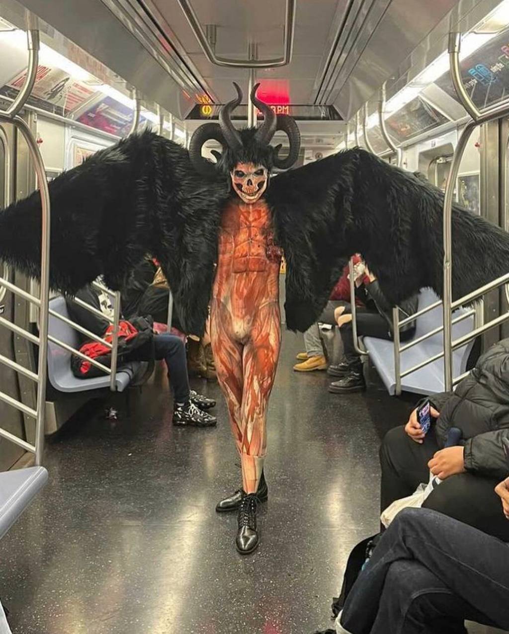 SubwayCreatures demonio A imagem mostra um homem fantasiado com asas pretas enormes, chifres e maquiagem.
